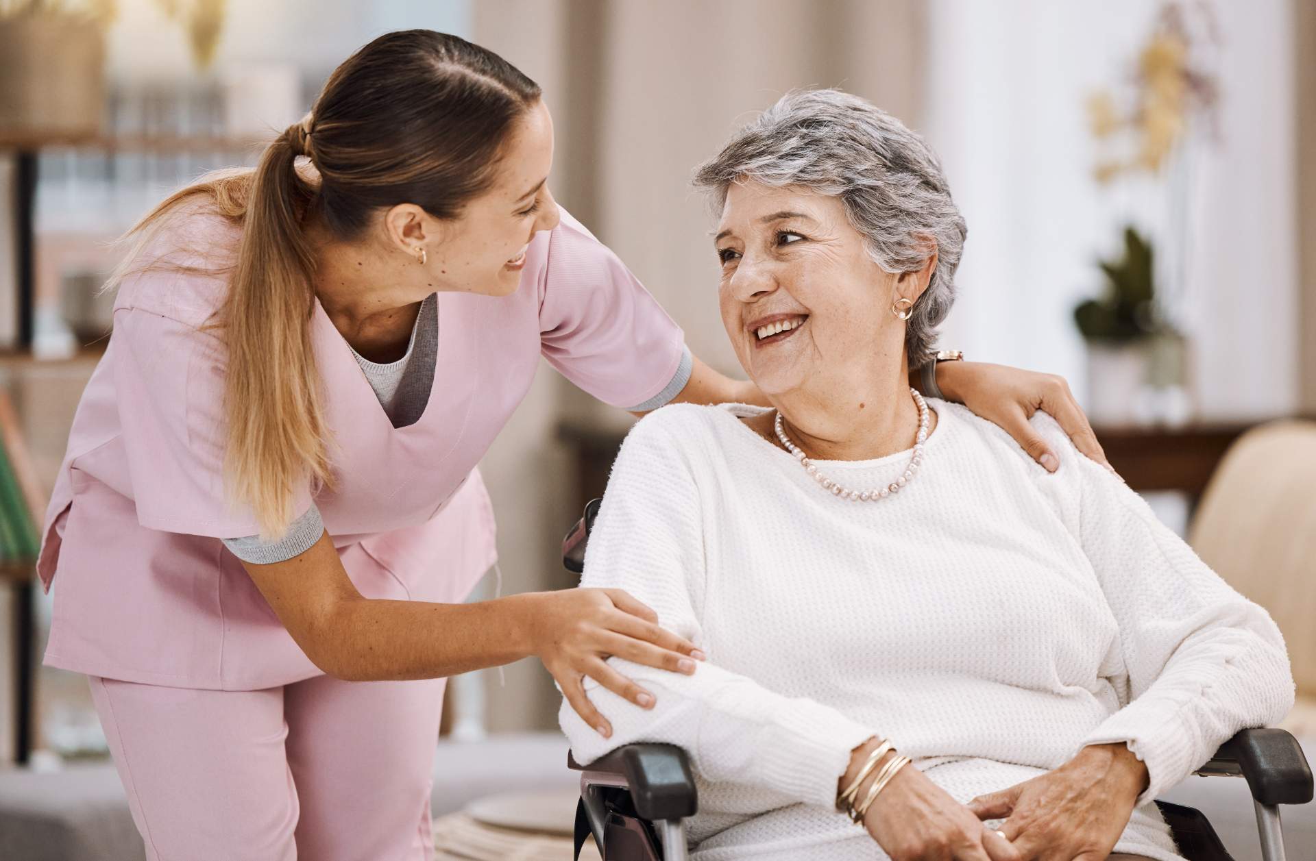 Caregiver assisting elderly woman in wheelchair
